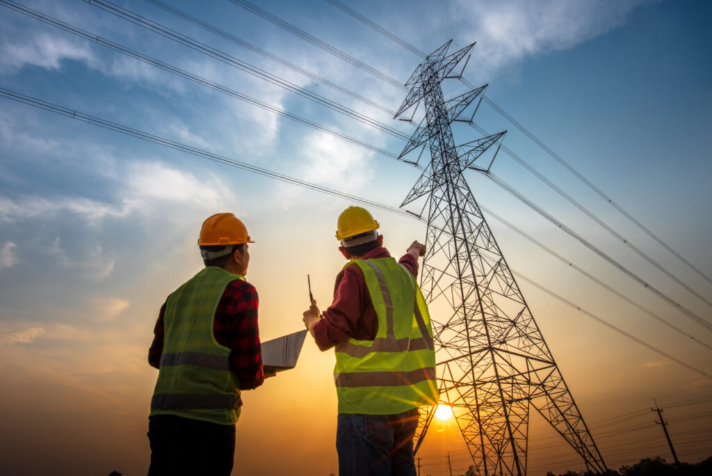 Zwei Elektrotechniker arbeiten an einem Strommast bei Sonnenuntergang als Symbol für die Axpo Case Study baseVISION