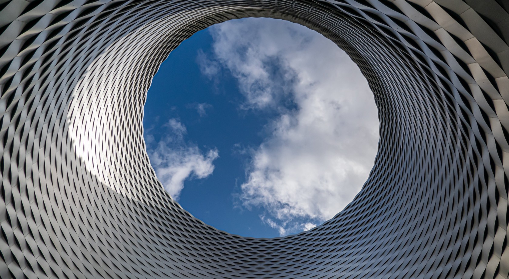 Blick vom Innenhof eines hohen Gebäudes in den Himmel mit Wolken als Symbol für die MCH Group Case Study von baseVISION