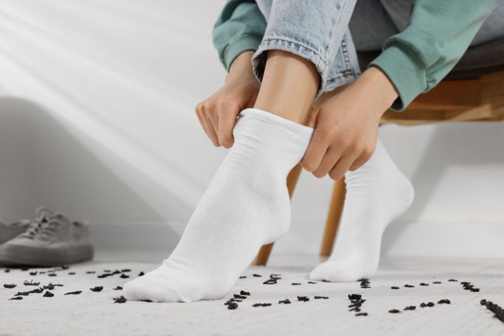 Eine Frau, die auf einem Stuhl sitzt und ihre weissen Socken anzieht als Symbol für die Sigvaris Kompressionsstrümpfe Case Study von baseVISION