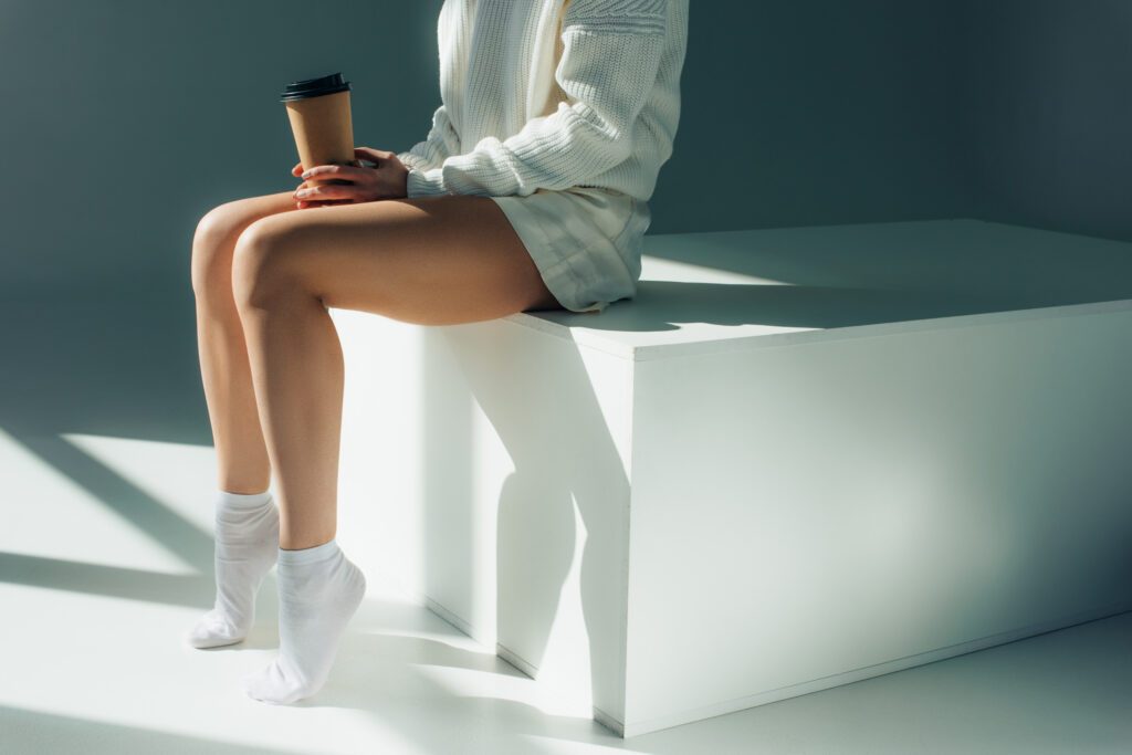 Eine Frau, die in Socken auf einem Absatz sitzt und einen Kaffeebecher in der Hand hält als Symbol für die Sigvaris Kompressionsstrümpfe Case Study von baseVISION